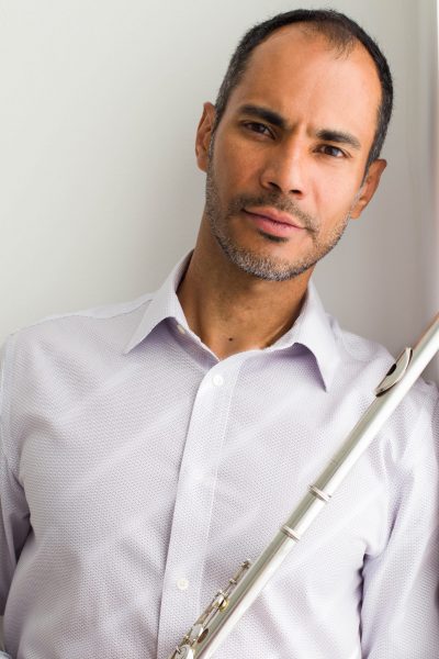 A photo of a man in a white button down shirt holding a flute