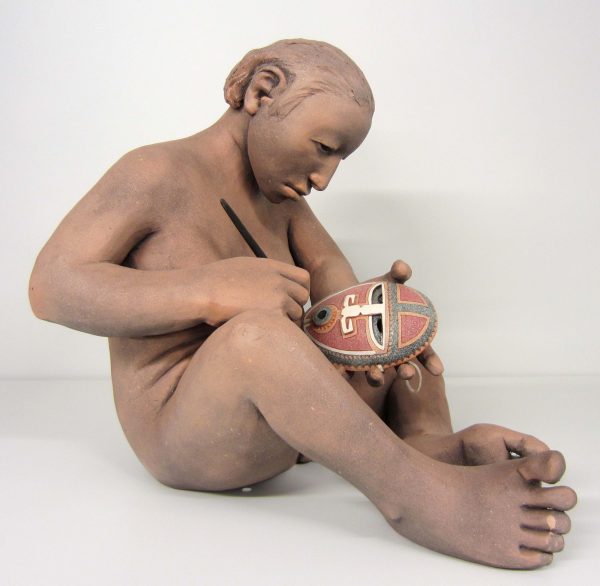 An image of cermaic pieces that is a native American person carving a maks
